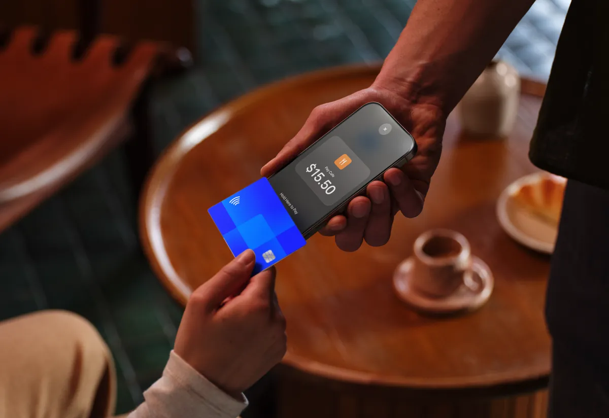 A merchant accepts a contactless card payment on iPhone at a cafe table